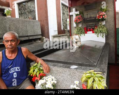 Caloocan, Philippinen. November 2023. Eine streunende Katze, die oben auf einem Grab gesehen wurde, während sie seine Pfote leckt. Menschen strömen zum Friedhof Sangandaan, um den UNDAS oder Allerheiligen in Caloocan City zu beobachten, trotz heftiger Regenfälle, um ihre verstorbenen Angehörigen zu besuchen. Die Philippine National Police (PNP) Caloocan wurde außerhalb des Friedhofs eingesetzt, um die Ordnung und Sicherheit der Öffentlichkeit zu gewährleisten. Quelle: SOPA Images Limited/Alamy Live News Stockfoto