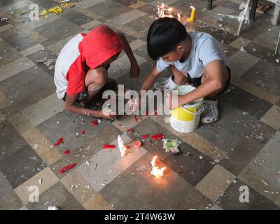 Caloocan, Philippinen. November 2023. Zwei Kinder spielen mit geschmolzenen Kerzenwachsen auf dem Sangandaan Cemetery. Menschen strömen zum Friedhof Sangandaan, um den UNDAS oder Allerheiligen in Caloocan City zu beobachten, trotz heftiger Regenfälle, um ihre verstorbenen Angehörigen zu besuchen. Die Philippine National Police (PNP) Caloocan wurde außerhalb des Friedhofs eingesetzt, um die Ordnung und Sicherheit der Öffentlichkeit zu gewährleisten. Quelle: SOPA Images Limited/Alamy Live News Stockfoto