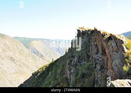 Ein Gebirgszug aus hohen Felsen mit geschichteten Felsformationen mit Blick auf einen tiefen Canyon. Altai, Sibirien, Russland. Stockfoto