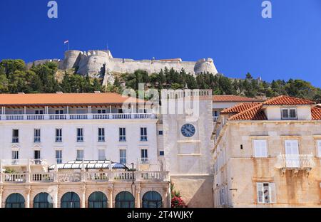 Blick auf Hvar, einschließlich der Festung auf dem Hügel und Gebäuden mit dem Uhrturm im Vordergrund Stockfoto