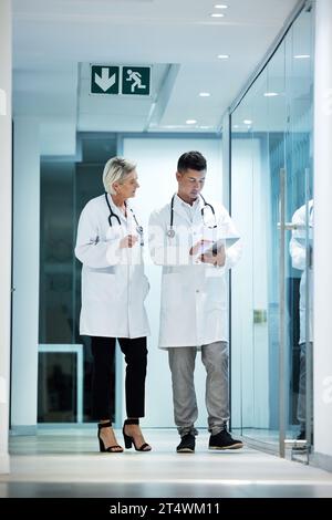 Tablette, Zusammenarbeit und Ärztinnen und Ärzte reden über die Planung einer Operation in einem modernen Krankenhaus im Gespräch über die Diagnose zusammen. Mann, Frau und Gesundheitswesen Stockfoto