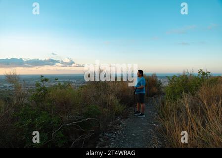 Ein übergewichtiger Mann stoppt sein Training, um die Landschaft am Morgen zu betrachten. Stockfoto