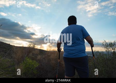 Ein übergewichtiger Mann stoppt sein Training, um die Landschaft am Morgen zu betrachten. Stockfoto