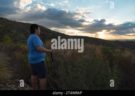 Ein übergewichtiger Mann stoppt sein Training, um die Landschaft am Morgen zu betrachten. Stockfoto