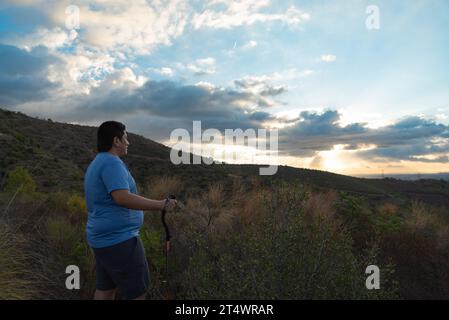 Ein übergewichtiger Mann stoppt sein Training, um die Landschaft am Morgen zu betrachten. Stockfoto