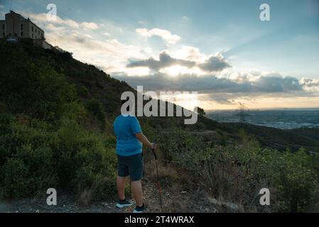 Ein übergewichtiger Mann stoppt sein Training, um die Landschaft am Morgen zu betrachten. Stockfoto