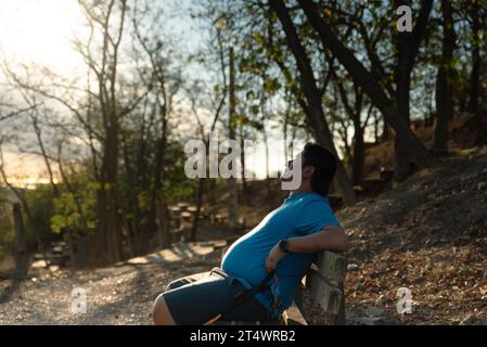 Ein übergewichtiger Mann stoppt sein Training, um die Landschaft am Morgen zu betrachten. Stockfoto