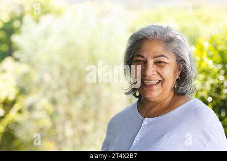 Porträt einer glücklichen zweirassigen Seniorin, die im sonnigen Garten lacht, Kopierraum Stockfoto