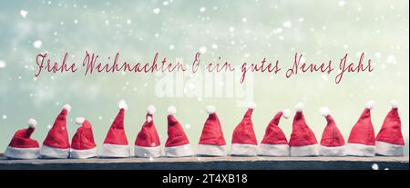 Viele Hüte des Weihnachtsmanns hintereinander auf einem rustikalen Holztisch mit den deutschen Worten Frohe Weihnachten und ein frohes neues Jahr, Panoramablick Stockfoto