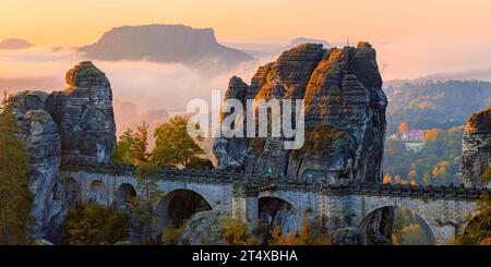 Ein breites 2:1-Panoramafoto eines Herbstsonnenaufgangs mit Blick vom Ferdinandstein mit vielen Herbstfarben an der Bastei-Brücke, Teil der Baste Stockfoto