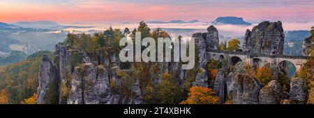 Ein breites 3:1 Panoramafoto eines herbstlichen Sonnenaufgangs mit Blick vom Ferdinandstein mit vielen Herbstfarben an der Bastei-Brücke, Teil der Baste Stockfoto