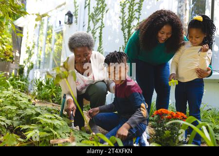 Glückliche afroamerikanische Mutter, Tochter und Enkelkinder arbeiten im Garten im Garten, Kopierraum Stockfoto