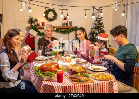 Glückliche Menschen feiern zu weihnachten und Neujahr zu Hause auf einem Tisch. Fröhliche ältere, Tochter, Sohn und Kind essen mit Stockfoto