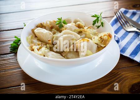 Ukrainischer Vareniky oder Pierogi gefüllt mit Kartoffeln und Pilzen, serviert mit gebratenen Zwiebeln. Holztischhintergrund. Hochwertige Fotos Stockfoto