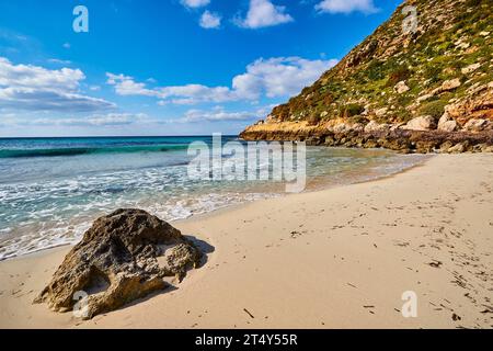 Weißer einsamer Strand, Felsen, blauer Himmel, weiße Wolken, Cala Pulcino, kleine Schlucht, Traumbucht, Insel Lampedusa, Provinz Agrigento, pelagische Inseln Stockfoto