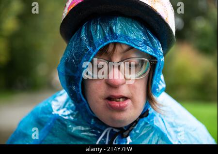 Nahaufnahme Porträt einer 41-Jährigen Frau mit Down-Syndrom, die einen Fahrradhelm und einen blauen Regenponcho trägt, Tienen, Flandern, Belgien Stockfoto