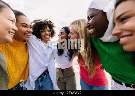 Sieben glückliche junge Erwachsene Frauen aus verschiedenen Kulturen, die gemeinsam im Freien lachen Stockfoto
