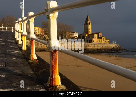 Kirche San Pedro am Strand von San Lorenzo, beleuchtet von der Sonne bei Sonnenaufgang in der Stadt Gijon, Asturien, Spanien Stockfoto