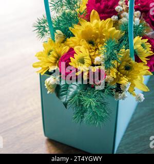 Festlicher mehrfarbiger Blumenstrauß in einem Papierkorb im Innenraum Stockfoto