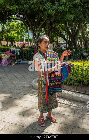 Guatemala, La Antigua - 20. Juli 2023: Nahaufnahme, junge Frau in traditioneller bunter Kleidung versucht jake Plastikschmuck und sc zu verkaufen Stockfoto