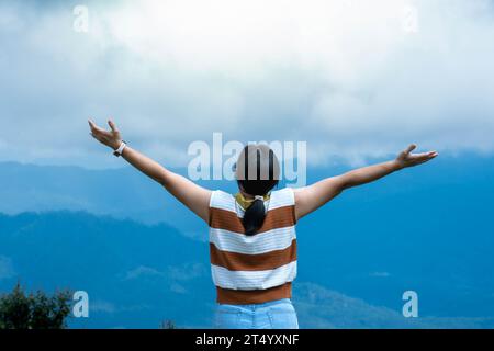 Weibliche Reisende genießen die Schönheit der Natur auf dem Berg und sehen die üppigen Bäume im tropischen Wald. Hipster-Frau hebt die Arme und enjo Stockfoto