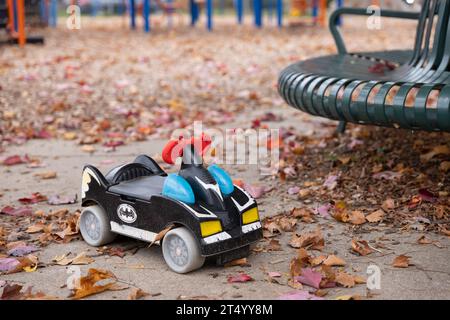 Toy Batmobil fährt im Herbst in einem Park mit Blättern auf dem Boden Stockfoto