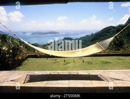 Seychellen. Mahé. Blick auf die Küste mit Cerf Island von der Hausterrasse mit Hängematte. Stockfoto