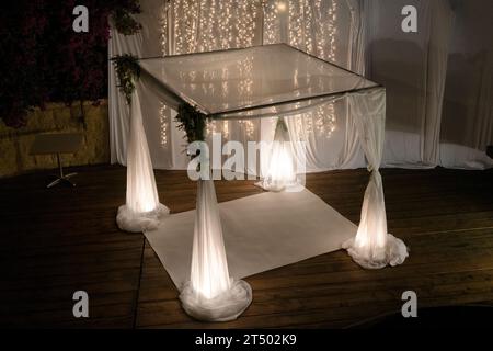 Eine Chuppah oder ein Baldachin aus weißem Spitzenstoff wird für eine jüdische Hochzeitszeremonie vorbereitet. Stockfoto