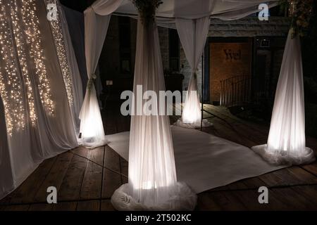 Eine Chuppah oder ein Baldachin aus weißem Spitzenstoff wird für eine jüdische Hochzeitszeremonie vorbereitet. Stockfoto