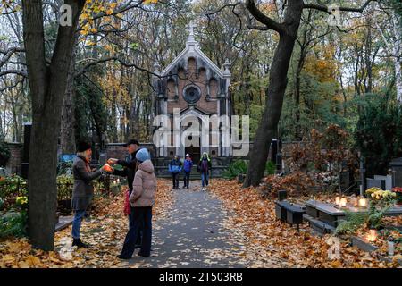 Warschau, Polen. November 2023. Am Allerheiligen-Tag auf dem evangelisch-Augsburger Friedhof in Warschau spazieren die Menschen durch den Friedhof. Allerheiligen (oder Dzie? Zaduszny (Polnisch) ist ein Feiertag in Polen. Es ist eine Gelegenheit, an verstorbene Verwandte zu erinnern. An diesem Tag bringen die Menschen Blumen, typischerweise Chrysanthemen, und Kerzen auf Friedhöfe. Der gesamte Friedhof ist voller Lichter in der Dunkelheit. Der Evangelisch-Augsburger Friedhof ist ein historischer lutherischer evangelischer Friedhof im Westen von Warschau. Seit seiner Eröffnung im Jahr 1792 sind mehr als 100.000 Menschen in buri ansässig Stockfoto