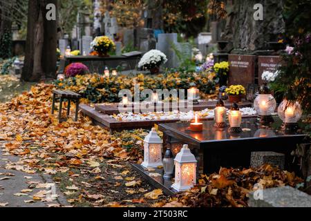 Warschau, Polen. November 2023. Am Allerheiligen auf dem evangelisch-Augsburger Friedhof in Warschau stehen Blumen und beleuchtete Kerzen auf den Gräbern. Allerheiligen (oder Dzie? Zaduszny (Polnisch) ist ein Feiertag in Polen. Es ist eine Gelegenheit, an verstorbene Verwandte zu erinnern. An diesem Tag bringen die Menschen Blumen, typischerweise Chrysanthemen, und Kerzen auf Friedhöfe. Der gesamte Friedhof ist voller Lichter in der Dunkelheit. Der Evangelisch-Augsburger Friedhof ist ein historischer lutherischer evangelischer Friedhof im Westen von Warschau. Seit seiner Eröffnung im Jahr 1792 waren es mehr als 100.000 Menschen Stockfoto