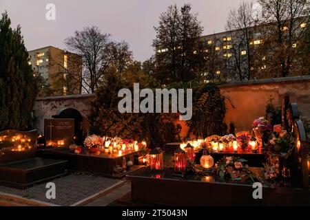 Warschau, Polen. November 2023. Am Allerheiligen auf dem evangelisch-Augsburger Friedhof in Warschau stehen leuchtende Kerzen und Blumen auf den Gräbern des Friedhofs unweit von Wohnhäusern. Allerheiligen (oder Dzie? Zaduszny (Polnisch) ist ein Feiertag in Polen. Es ist eine Gelegenheit, an verstorbene Verwandte zu erinnern. An diesem Tag bringen die Menschen Blumen, typischerweise Chrysanthemen, und Kerzen auf Friedhöfe. Der gesamte Friedhof ist voller Lichter in der Dunkelheit. Der Evangelisch-Augsburger Friedhof ist ein historischer lutherischer evangelischer Friedhof im Westen von Warschau. Seit ITS Stockfoto