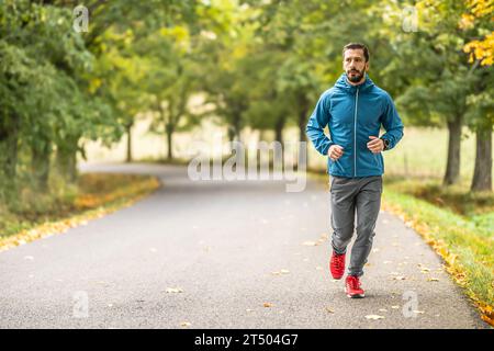 Ein junger Mann trainiert und läuft in einem Herbstpark. Stockfoto
