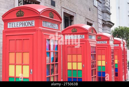 Eine Reihe klassischer K6-Telefonboxen in Rot, dekoriert mit LGBTQ-Regenbogenfarben in Broad Court, Covent Garden, London, England, Großbritannien Stockfoto