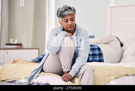 Traurig, Scheidung und ältere Frau im Schlafzimmer mit Depression über Untreue in Ehe mit Kampf. Ehe, wütend und ältere Frau mit Angst oder Stockfoto