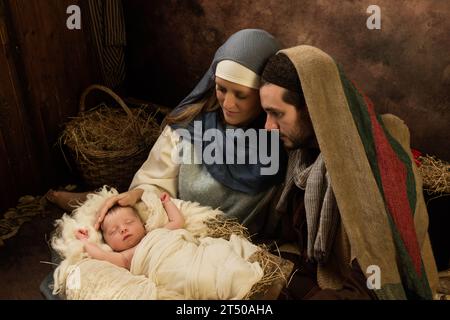 Ein Paar, das mit seinem 8 Tage alten kleinen Neugeborenen eine Weihnachten-Live-Krippe nachführt Stockfoto