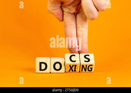 Dokumente oder Doxing-Symbol. Concept Words Docs Doxing auf Holzblock. Schöner oranger Tisch mit orangefarbenem Hintergrund. Geschäftsmann Hand. Geschäftsdokumenten oder Docking-Lösungen Stockfoto