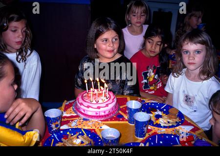 Mädchen feiert den 8. Geburtstag mit Freunden auf einer Party und macht sich bereit, Kerzen am Geburtstagskuchen Surrey England auszublasen Stockfoto