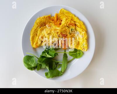 Rührei mit Grünzeug auf weißem Teller und weißer Tisch von oben Stockfoto