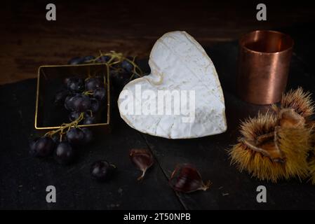 Stillleben mit Neufchatel Normand-Käse (A.O.P.), Käseformen und Trauben Stockfoto