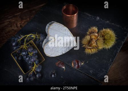 Stillleben mit Neufchatel Normand-Käse (A.O.P.), Käseformen und Trauben Stockfoto