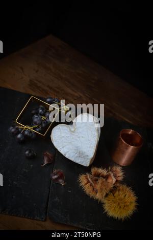 Stillleben mit Neufchatel Normand-Käse (A.O.P.), Käseformen und Trauben Stockfoto