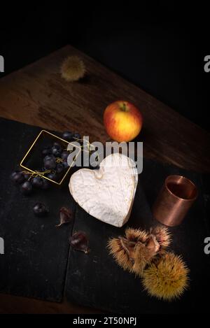 Stillleben mit Neufchatel Normand-Käse (A.O.P.), Käseformen und Trauben Stockfoto