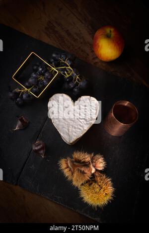 Stillleben mit Neufchatel Normand-Käse (A.O.P.), Käseformen und Trauben Stockfoto