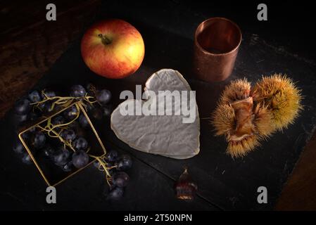 Stillleben mit Neufchatel Normand-Käse (A.O.P.), Käseformen und Trauben Stockfoto