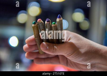 Menschliche Hand hält rustikale Holzfarben, mit unscharfem Hintergrund und Beleuchtung Stockfoto