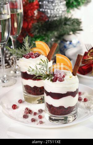 Weihnachts-Cranberry-Dessert-Tiramisu mit Mascarpone und Schlagsahne, Schokoladen-Kekskrümel und Cranberry-Marmelade, garniert mit Orangenscheiben, Dose Stockfoto