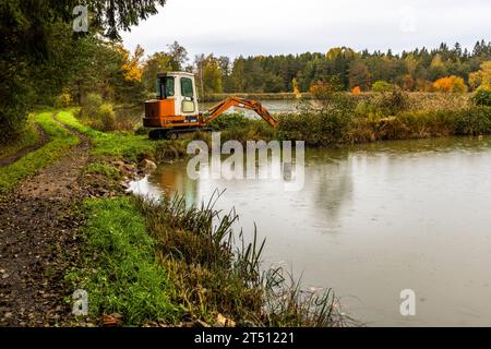 Bagger an einem Karpfenteich in der Oberpfalz. Die Fischzucht findet in Kettenteichen statt, die hintereinander gebaut sind und einen leichten Höhenunterschied aufweisen. Wenn ein Teich geleert wird, wird das Wasser im darunter liegenden Teich gesammelt, der bereits ausgefischt wurde. Dies spart Wasser in der Teichzucht. Mitterteich (VGem), Deutschland Stockfoto