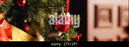Stilvolles, weihnachtliches Interieur. Komfortheim mit Kamin. Geschenkboxen unter dem Weihnachtsbaum mit roten Kugeln im dunklen Wohnzimmer Stockfoto