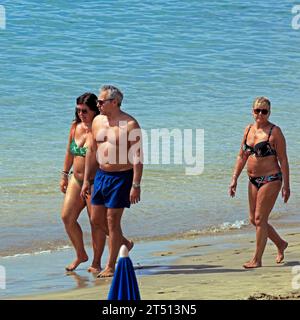 Drei Personen genießen den Strand Playa Dorada auf Lanzarote. Vom März 2023 Stockfoto